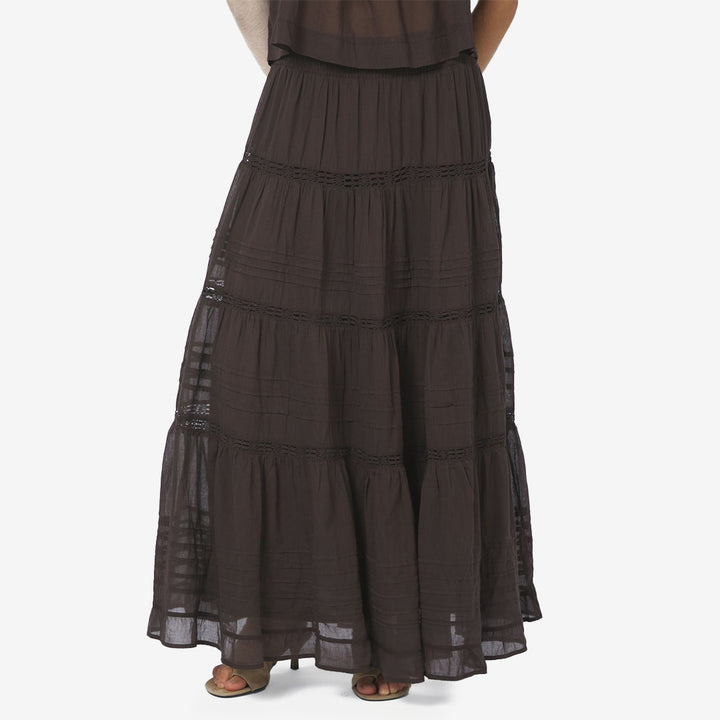 Felicia S Voile Skirt i mörkbrun färg, maxi-kjol i bomull med smockmidja och dekorativa banddetaljer.