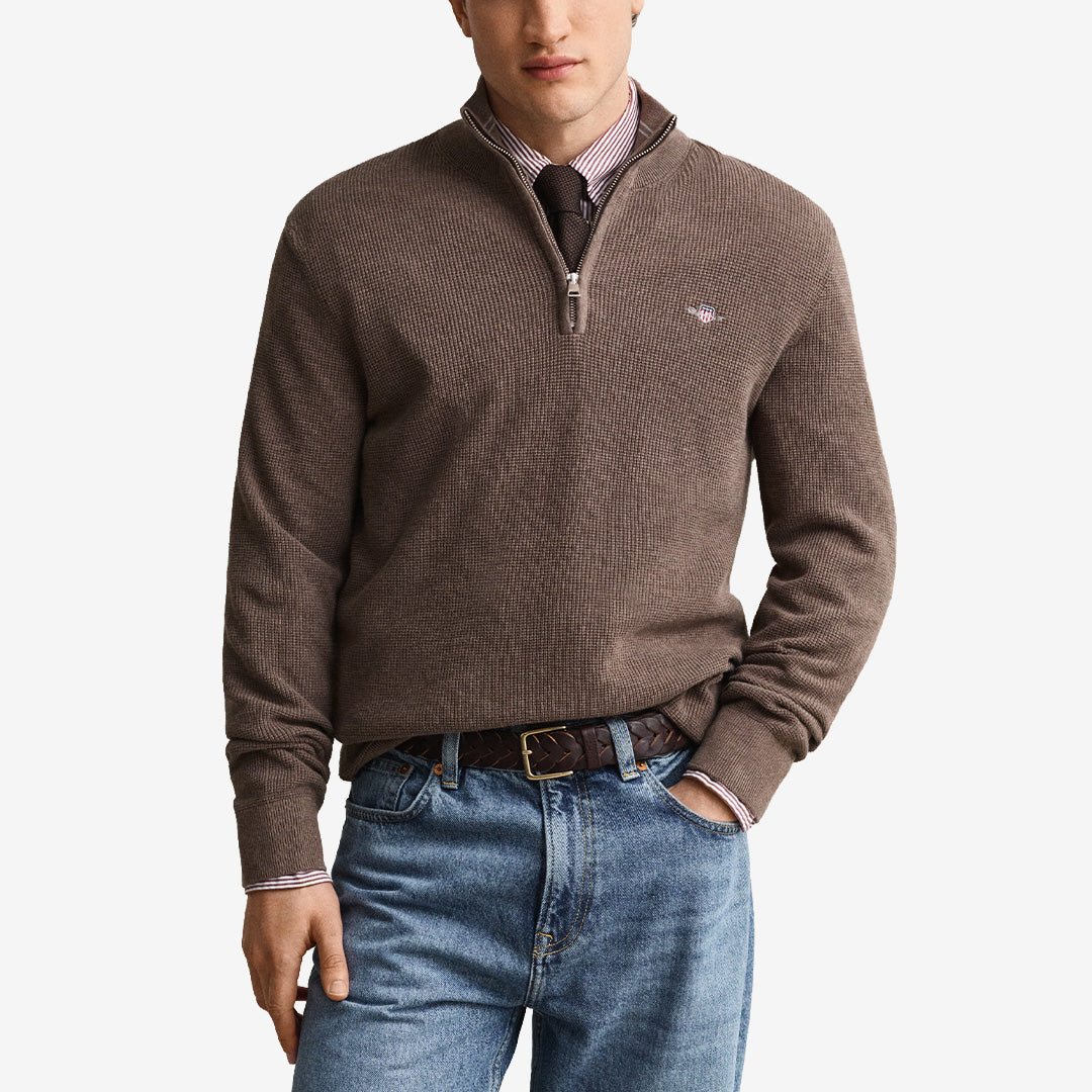 Stickad half zip tröja från Gant för herr i dk hazelnut melange med ribbad krage, våffelstruktur och broderad logotyp.