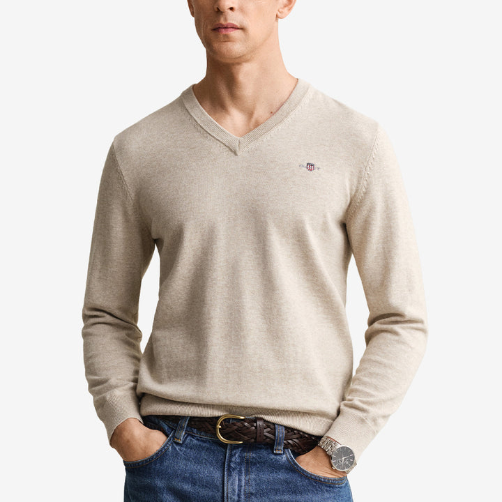 V-ringad tröja från Gant i 100 % bomull i färgen oat melange med ribbade detaljer och broderad sköld på bröstet