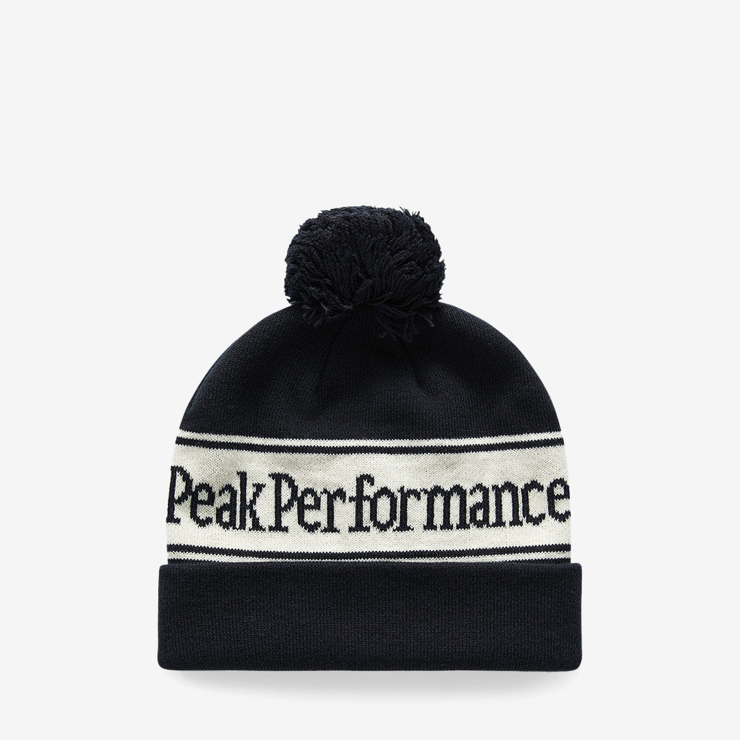 Svart och vit Peak Performance Pow mössa med retrolook, logotyp och boll på toppen

