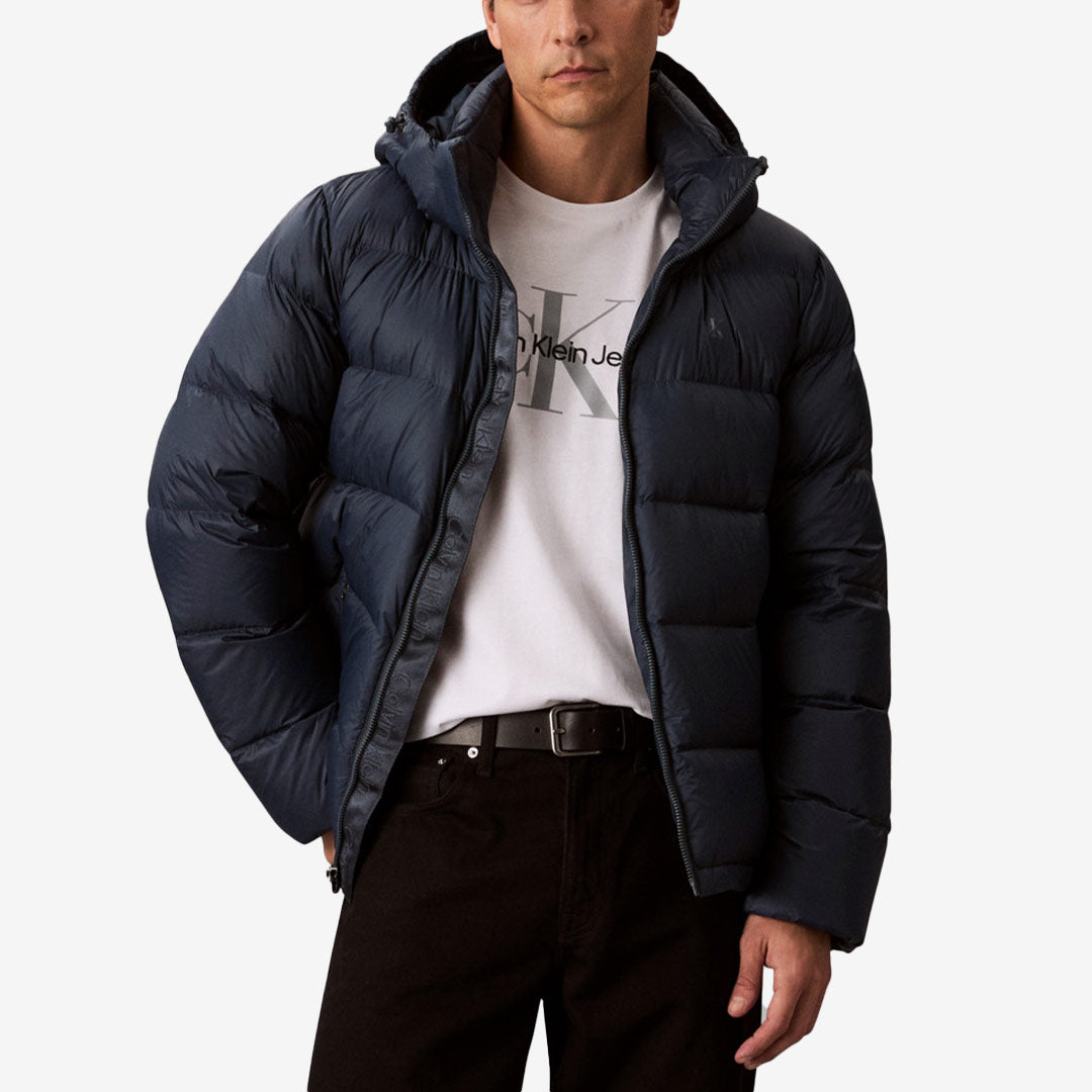 Mörkblå vadderad dunjacka från Calvin Klein med avtagbar huva, ståkrage och tvåvägsdragkedja framtill.